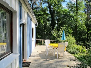 A patio with a table and chairs, a blue umbrella, and a view of trees and greenery. - Waldhäuser by Interhome (Himmelpfort)