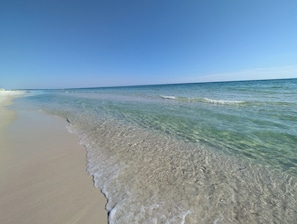 A beach with clear shallow waters and a sandy shore.
