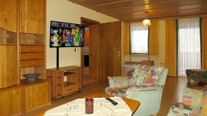 Una sala de estar con armarios de madera, un televisor, un sofá y una mesa con un control remoto.