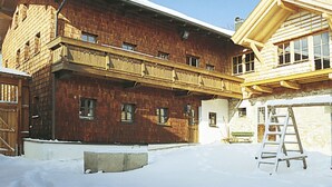 Un edificio de madera de dos pisos, con techo nevado y balcón de madera.