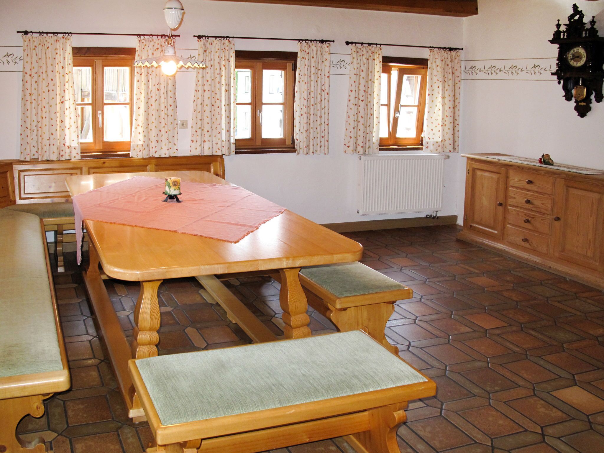 A dining room with a wooden table, benches, and a radiator.