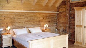 Un dormitorio de madera con una cama, dos mesitas de noche y un armario.