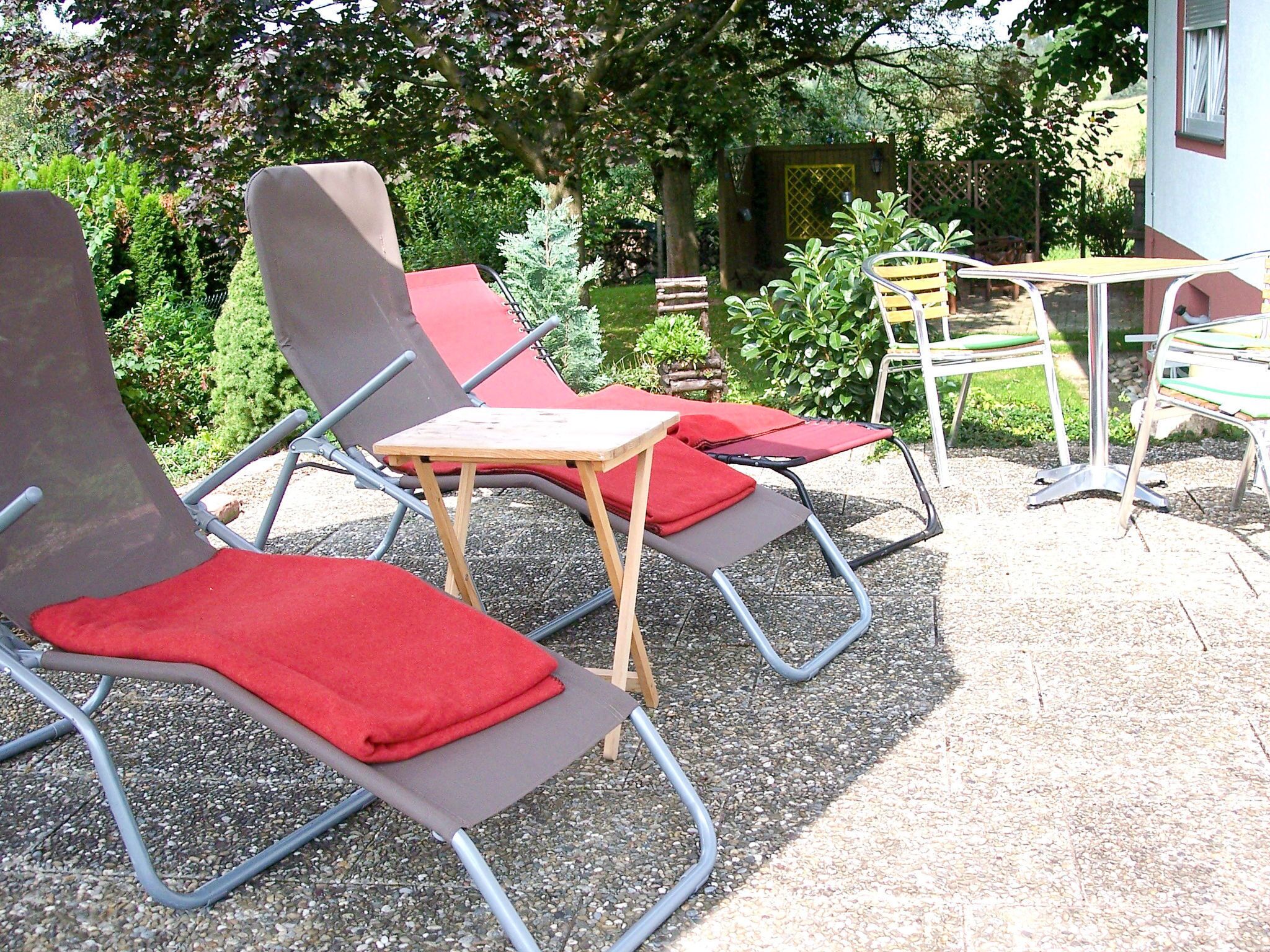 Ein Patio mit Gartenmöbeln, darunter Lounge-Stühle und ein kleiner Tisch.