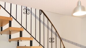 Una escalera de madera con barandillas de metal negro y una pared blanca.