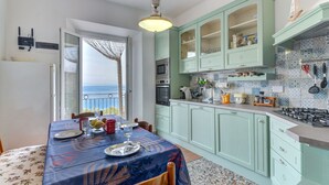 A kitchen with a dining area, a view of the sea, and a balcony.