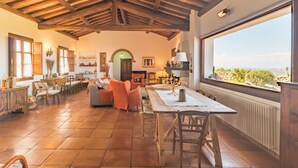 A spacious living area with a high wooden ceiling, a large window offering a view of the landscape, and a cozy seating arrangement. - Vacation home Rita by Interhome (Palau)