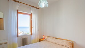 A bedroom with a bed, a window with curtains, a bedside lamp, and a view of the sea. - Villa Teresa by Interhome (Peschici)