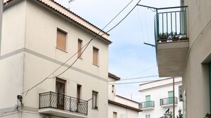 A narrow street with multi-story buildings, balconies with metal railings, and a parked car. - Villa Teresa by Interhome (Peschici)