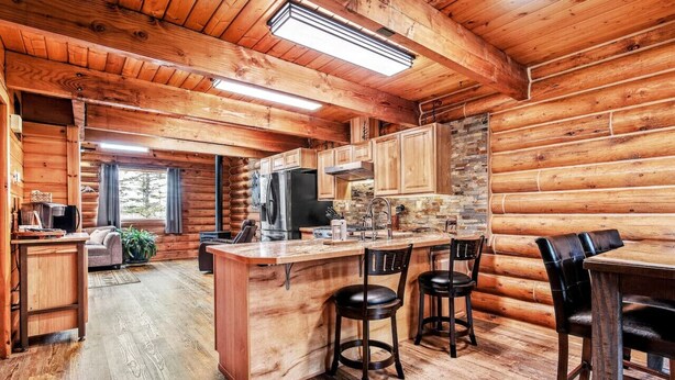 A log cabin interior with a kitchen, dining area, and living space.