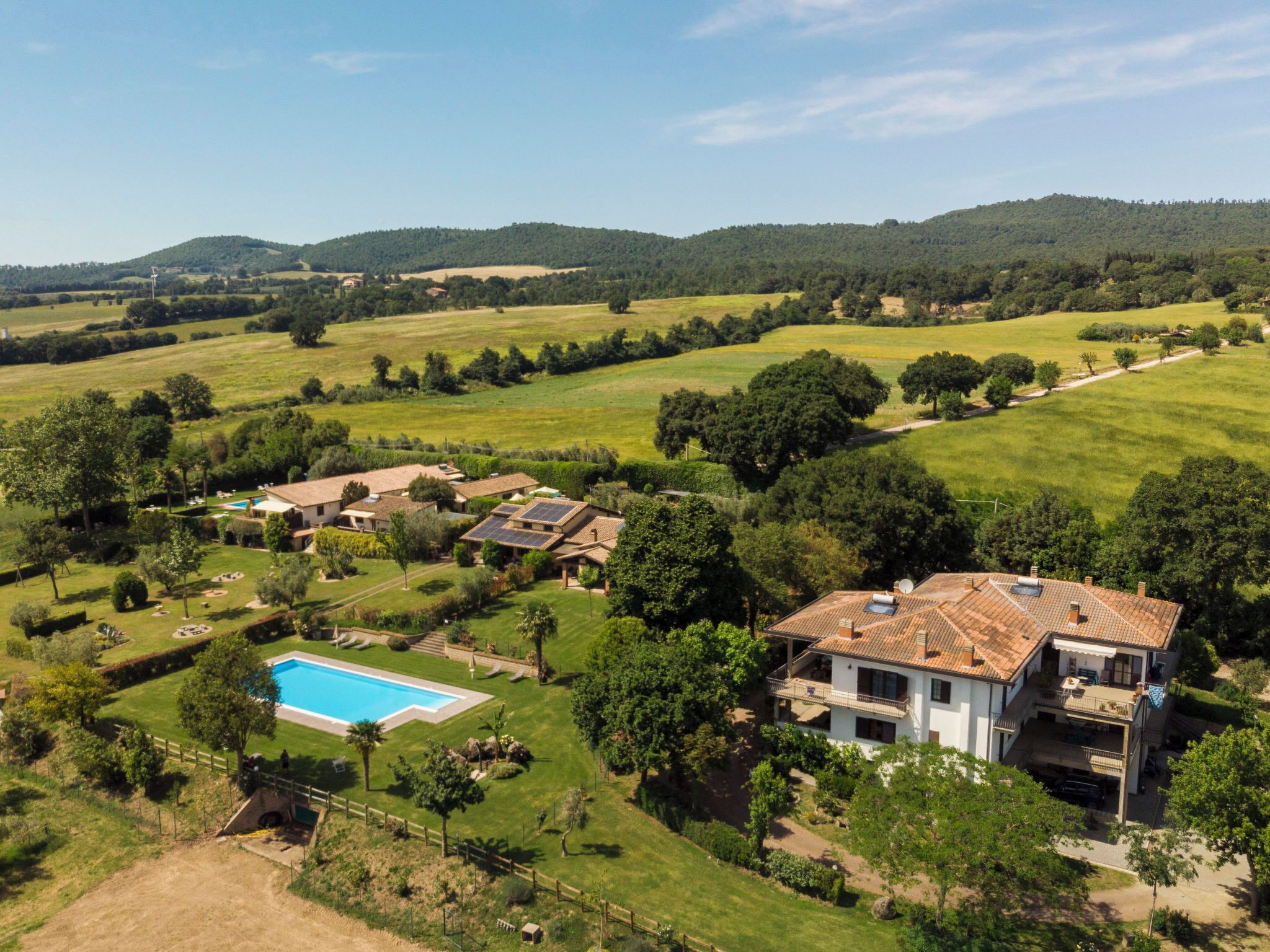 A residential area with a swimming pool, solar panels, and a large house with a tiled roof.