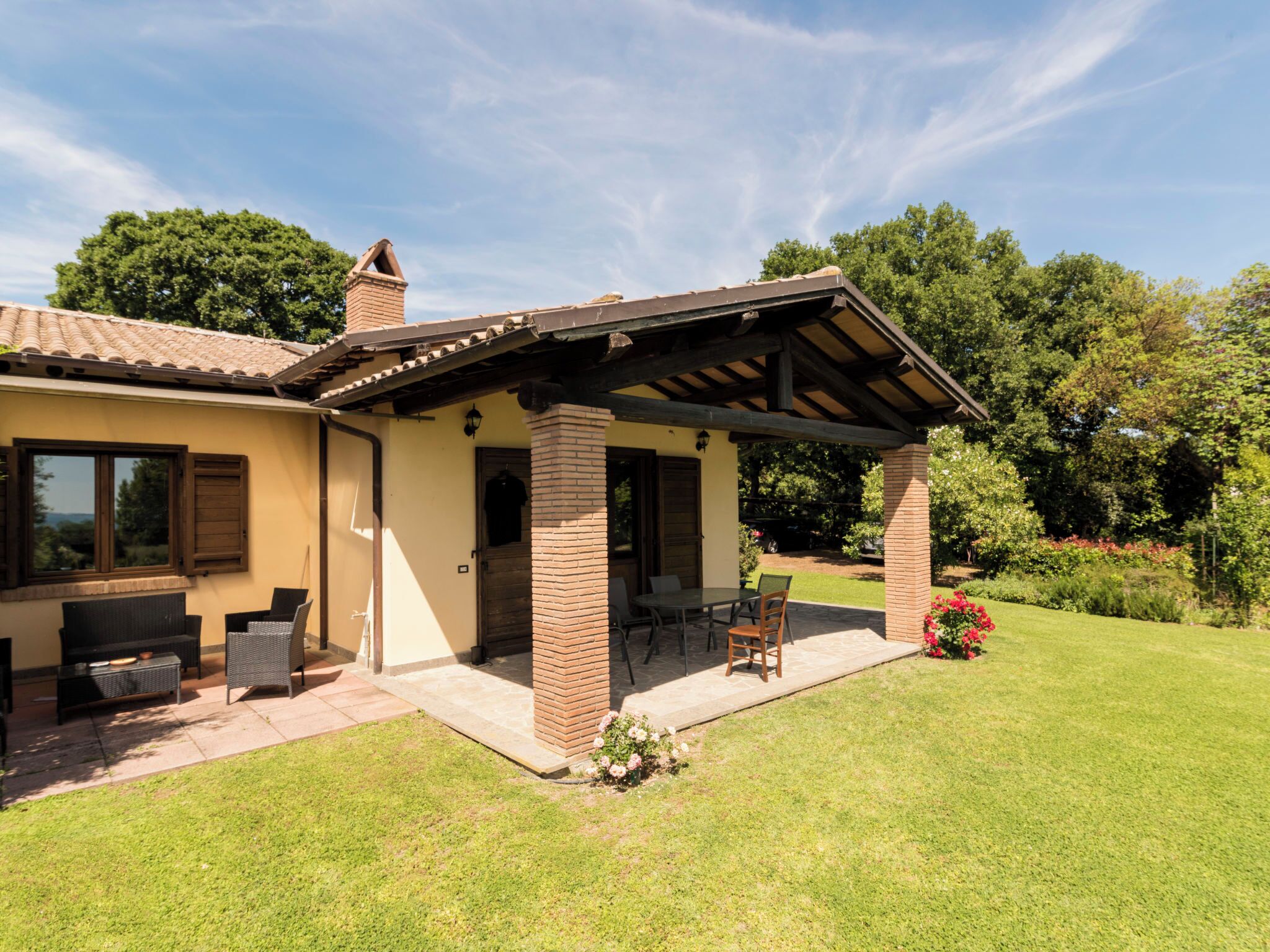 Une maison avec un patio, un espace salon extérieur et un jardin.