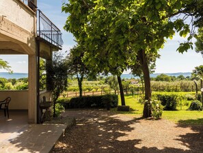 A covered outdoor area with a stone bench, a pergola, and a view of a vineyard. - Rosa Alba by Interhome (Lago di Bolsena)