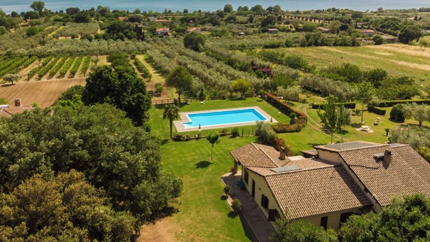 A villa with a swimming pool, surrounded by lush greenery and a view of the sea.