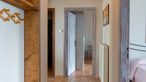 A hallway with a wooden door frame, a radiator, and a bed with a pink blanket.