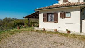 A two-story house with a tiled roof, wooden shutters, and a gravel driveway. - Querceto by Interhome (Sassofortino)