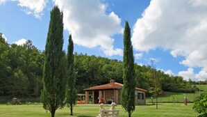 A stone building with a tiled roof, surrounded by a grassy lawn and tall cypress trees. - Vacation home Dilia by Interhome (Boccheggiano)