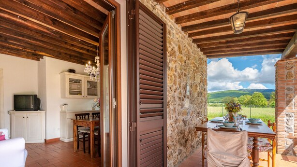 A cozy room with a stone wall, a wooden ceiling, and a view of the countryside. - Vacation home Dilia by Interhome (Boccheggiano)