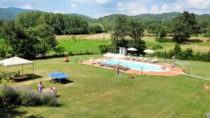 A pool area with lounge chairs and umbrellas, surrounded by green fields and trees. - Vacation home Dilia by Interhome (Boccheggiano)
