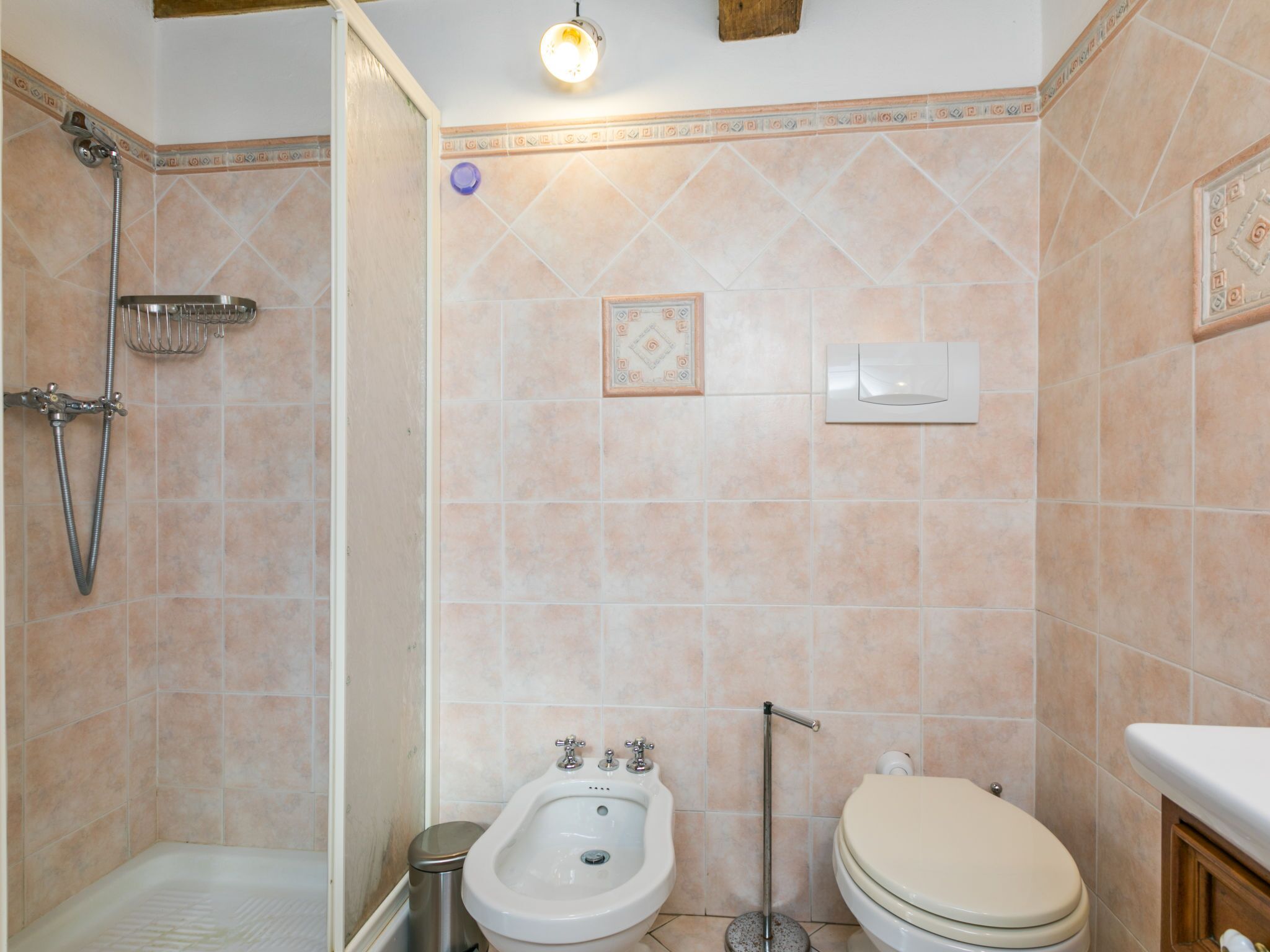 Une salle de bain équipée d’une douche, d’un bidet, de toilettes et d’une petite poubelle.