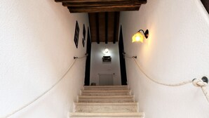 Una escalera con barandilla de cuerda, una lámpara y un radiador al fondo.
