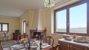 Ein Esszimmer mit Kamin, einem gedeckten Tisch und Blick ins Freie durch ein großes Fenster.