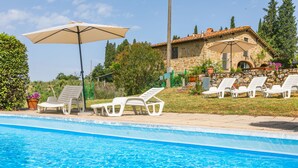 A swimming pool with white lounge chairs and a beige umbrella.