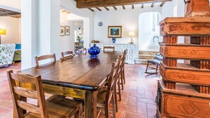 Un coin repas avec une table et des chaises en bois, un bol décoratif bleu et un escalier avec une rampe en bois.