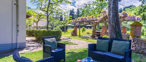Un espacio al aire libre con mobiliario de mimbre y una mesa dispuesta con una bebida y pasteles.