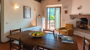 Uma sala de jantar com uma mesa de madeira, cadeiras, uma cesta de frutas e uma poltrona amarela.