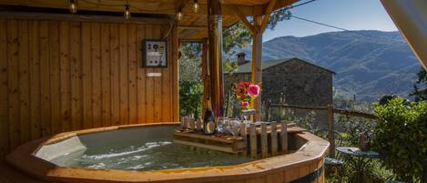 A wooden hot tub with a wooden deck and a view of mountains.