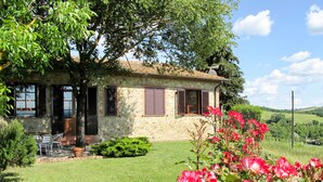 A stone house with a garden, a lawn, and a view of the countryside.