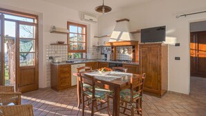 A kitchen with a dining table, chairs, and a TV mounted above the counter.