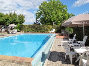 A rectangular swimming pool with a tiled edge, surrounded by white plastic lounge chairs and tables, and shaded by umbrellas. - Cignanbianco - Alba e Tramonto by Interhome (Castellina in Chianti)