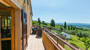 Un balcon offrant une vue sur un vignoble et des collines ondoyantes.