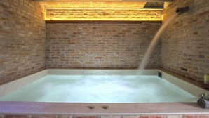 Ein raum mit Ziegelwänden und einer großen, leeren Badewanne.