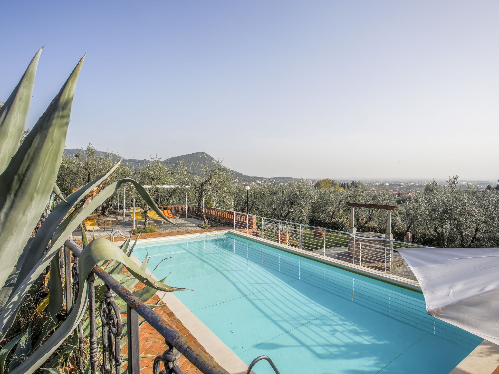 A swimming pool with a view of a city and hills in the background.