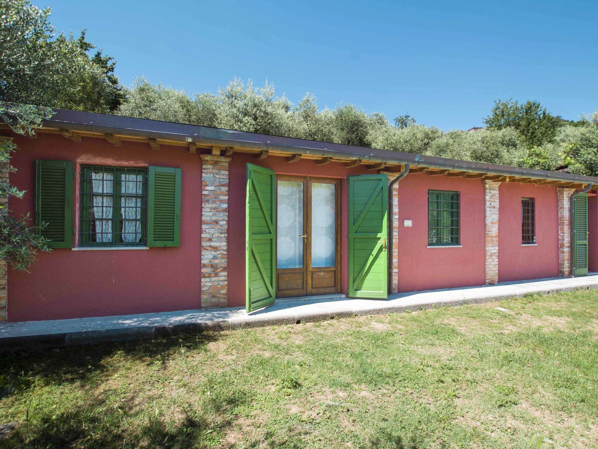 A red building with green shutters and a wooden door.