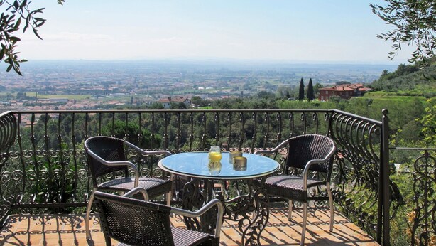 A round table with four chairs on a balcony with a metal railing, overlooking a cityscape. - Vacation home Iacopo by Interhome (Montecatini Terme)
