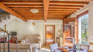 A cozy living room with a sofa, a dining table set with plates and glasses, and a staircase with a wooden railing. - Vacation home Iacopo by Interhome (Montecatini Terme)