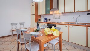 A modern kitchen with wooden cabinets, a dining table set for four, and a hanging light fixture.