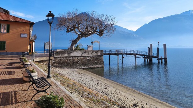 A waterfront promenade with benches, a lamp post, and a stone wall.