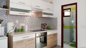 A modern kitchen with white cabinets, a built-in oven, and a tiled backsplash. - Borovina by Interhome (Korčula/Korčula)