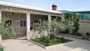 A covered outdoor area with a swimming pool, stone walls, and a small garden with various plants. - Vacation home Lucije by Interhome (Brač/Splitska)