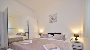 A modern bedroom with a large bed, bedside tables, a mirror, and a wall-mounted artwork. - Vacation home Lucije by Interhome (Brač/Splitska)