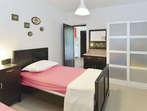 A bedroom with a bed, nightstand, dresser, and a bathroom with a sink and mirror. - Apartment Lila by Interhome (Brač/Splitska)