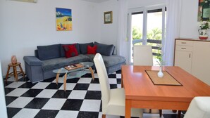 A living room with a checkered floor, a sofa, a dining table, and a view of the outdoors. - Apartment Nina by Interhome (Omiš)