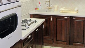 A kitchen with wooden cabinets, a stove, a sink, and a window above the sink.