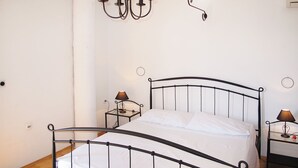 A bedroom with a metal bed frame, two bedside tables with lamps, a wall-mounted light fixture, and a door.