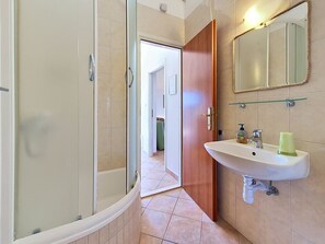 Een badkamer met een douche, wastafel en spiegel.