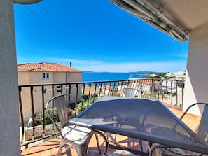 Een balkon met een tafel en stoelen, met uitzicht op de kust.